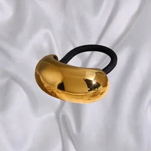 Élastique à cheveux doré en forme de haricot poli sur fond de soie blanche élégant