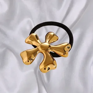 Golden liquid metal flower hair tie with black elastic band on white silk backdrop
