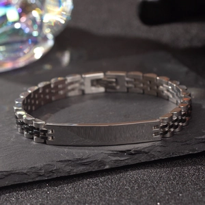 Detailed close-up of a silver stainless steel jubilee watch band bracelet on stone