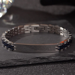 Detail view of silver stainless steel ID bracelet with blue accents on rock background