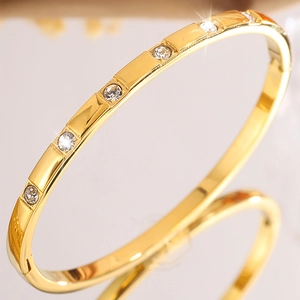 Detail view of gold-plated bangle featuring alternating rectangular blocks and white zircons