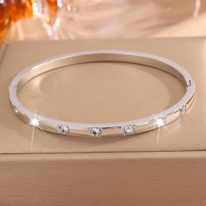 Detailed view of silver stainless steel bangle with inlaid diamonds on a jewelry box