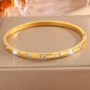 Detail of gold titanium steel bangle with inlaid crystals on a luxury display box