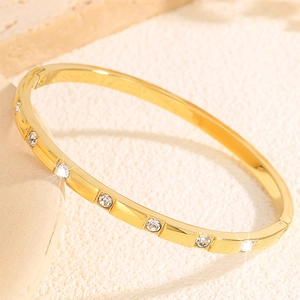 Close-up of a gold-plated stainless steel hinged bangle featuring bezel-set rhinestones