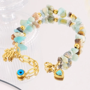 Detail eines Boho-Steinarmbands mit Herzanhänger und goldenem Auge-Anhänger