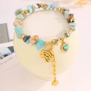 Makroaufnahme eines Perlenarmbands mit goldenem Horusauge und Herzanhängern aus Stein