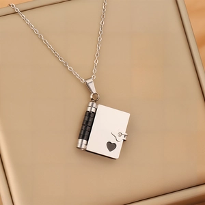 Vue macro d'un collier médaillon enveloppe en acier sur un coffret à bijoux beige
