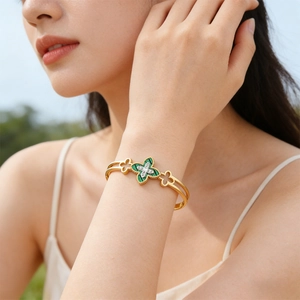Detail of gold clover bangle with green malachite texture and sparkling accents on wrist