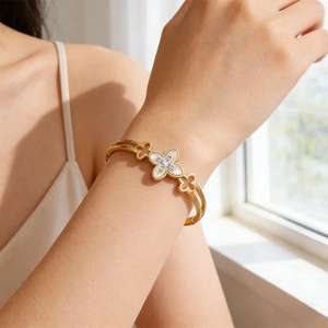 Detailed close-up of golden clover bracelet with white mother of pearl and small diamonds