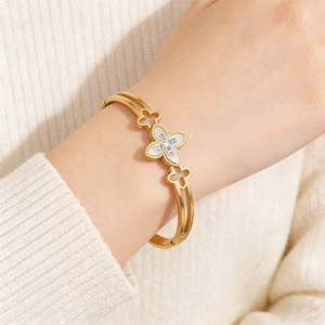 Detail of gold clover bangle with mother of pearl and crystal inlay on a dual band