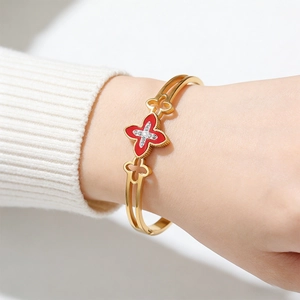 Detail of gold hollowed bangle with red clover motif and sparkling cross diamonds