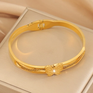 Makroaufnahme eines goldenen Schmetterlingsarmbands mit griechischem Mäandermuster-Detail