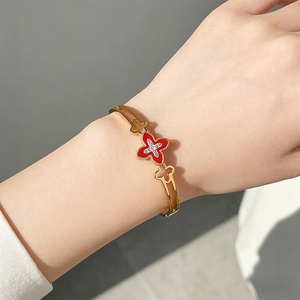 Detailed close-up of clover bangle with red inlay and diamonds on gold stainless steel