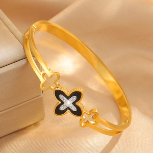 Macro detail of gold clover bangle with black inlay and sparkling white zircons
