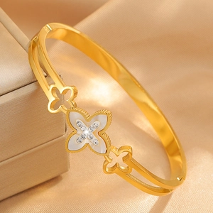 Close-up of golden clover bangle with white shell inlay and sparkling crystals detail