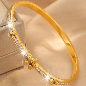Detail of gold floral bangle with green gemstone and a row of sparkling crystals