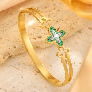 Macro shot of gold four-leaf clover bracelet with green malachite texture inlay