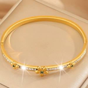 Close-up of golden floral bracelet with square zircons and green gemstone flower centers