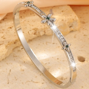 Macro detail of silver bangle with green gemstone flowers and square pave diamonds