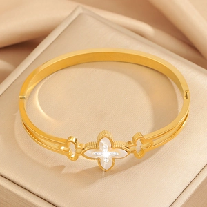 Macro detail of gold clover bracelet with white shell inlay and sparkling rhinestones
