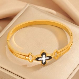Detailed close-up of gold clover bangle with black enamel and sparkling rhinestones