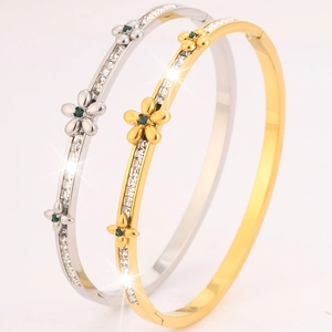 Macro shot of gold and silver flower bangles with cubic zirconia and green gemstones