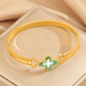 Close-up of gold clover bracelet featuring green malachite inlay and sparkling crystals