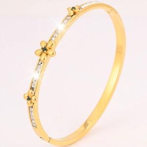 Detail of gold flower bangle featuring green stones and double row of square cubic zirconia