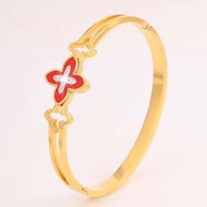 Detailed macro view of gold-plated bangle with red clover and sparkling crystals