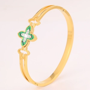 Close-up of gold clover bangle with green stone inlay and fine diamond accents