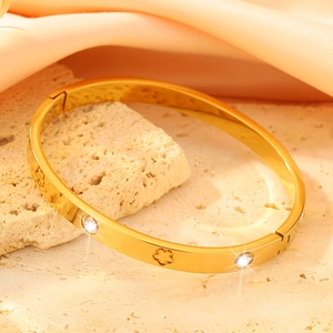 Macro-detail van de gouden armband met bloemmotief, kristallen en scharnier