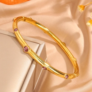 Detalle del brazalete de acero inoxidable dorado con diez circonitas púrpuras engastadas