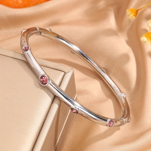 Primer plano de la pulsera estilo bambú de acero plateado con cristales rosas sobre caja