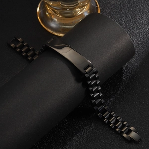 Detail of a black stainless steel link chain bracelet wrapped on a black display stand