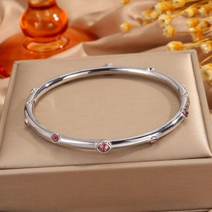 Detalle de pulsera de acero plateado con piedras rosas sobre elegante joyero de lujo
