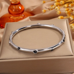 Detalle del brazalete de acero inoxidable plateado con piedras negras en soporte elegante