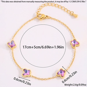 Détail du bracelet trèfle doré avec pendentifs papillons violets et chaîne de 17 cm de long
