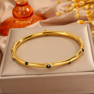 Brazalete bañado en oro de 18k con incrustaciones negras sobre una caja de regalo