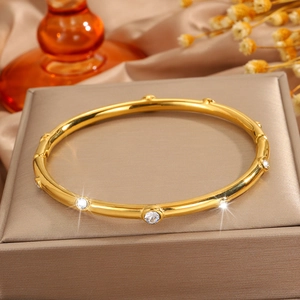Primer plano de brazalete de acero inoxidable dorado con diamantes sobre seda