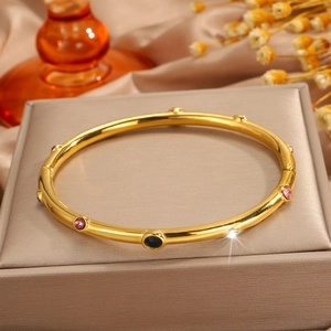 Detalle de brazalete bañado en oro de 18k con piedras de colores sobre fondo de satén