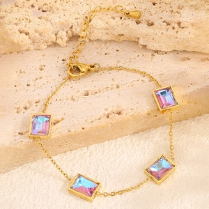 Détail du bracelet en chaîne dorée avec cristaux irisés sur un support en pierre
