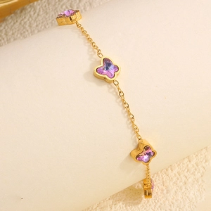 Détail d'un bracelet doré orné de délicats pendentifs papillons en cristal violet