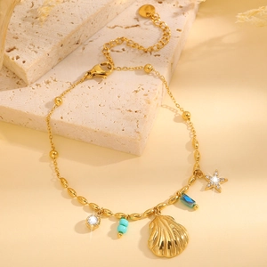 Détail d'un bracelet coquillage doré avec perle turquoise et étoile sur support pierre