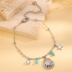 Détail d'un bracelet coquillage argenté avec perles turquoise et breloque étoile sur pierre