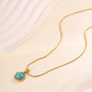 Vue détaillée du pendentif fleur turquoise dorée avec diamants et chaîne serpent