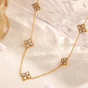 Collier élégant en acier titane doré avec cinq pendentifs trèfles en nacre blanche
