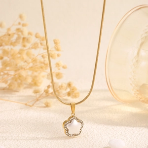Détail de la chaîne serpent dorée avec un pendentif fleur blanche incrusté de perles et zircons