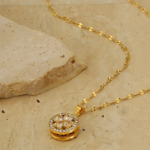 Macro detail of gold-plated clover pendant with sparkling zircons on stone background