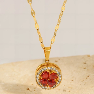 Close-up of a gold titanium clover necklace with red heart crystals and tiny diamonds