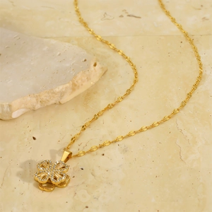 Macro detail of gold-tone four-leaf clover pendant necklace with sparkling crystals